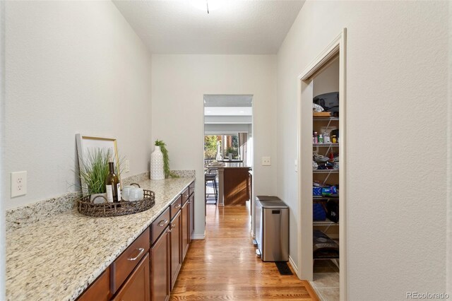 kitchen featuring a textured ceiling, light stone countertops, and light hardwood / wood-style flooring