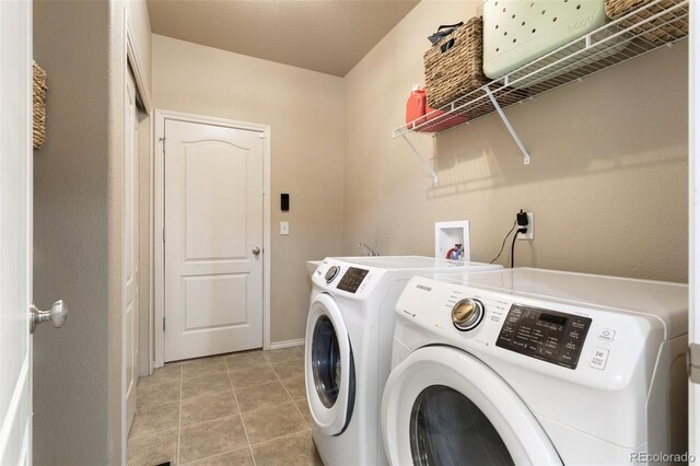 laundry area featuring a textured ceiling, light tile patterned floors, and washing machine and clothes dryer