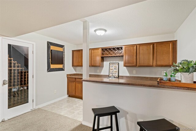 kitchen featuring light carpet, a breakfast bar area, and a textured ceiling