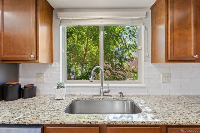 kitchen with dishwasher, sink, light stone counters, and tasteful backsplash