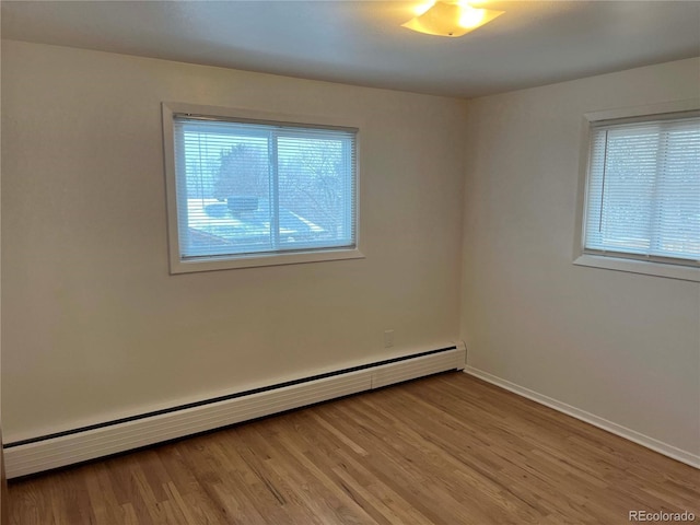 unfurnished room with light wood-type flooring, a wealth of natural light, and baseboard heating