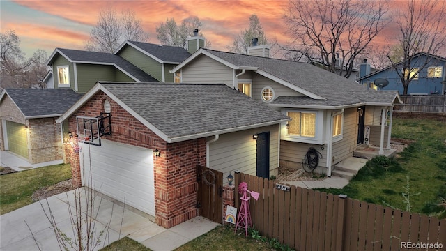 split level home with a garage, roof with shingles, fence, brick siding, and driveway