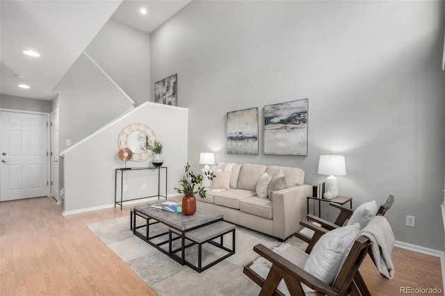 living room featuring a towering ceiling and light wood-type flooring