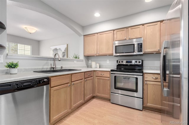 kitchen with stainless steel appliances, sink, light brown cabinets, and light hardwood / wood-style floors