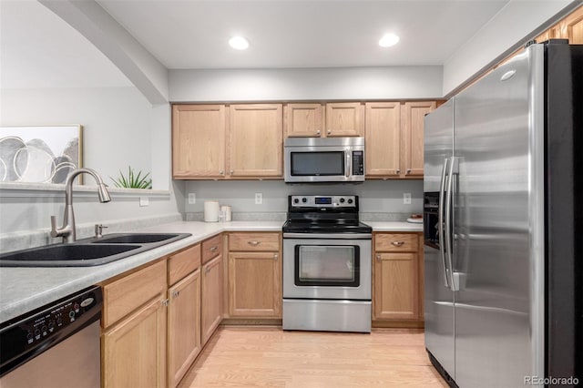 kitchen with stainless steel appliances, sink, light brown cabinets, and light wood-type flooring