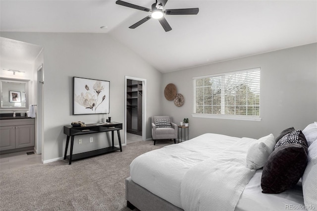 bedroom featuring lofted ceiling, sink, ensuite bathroom, light carpet, and a spacious closet