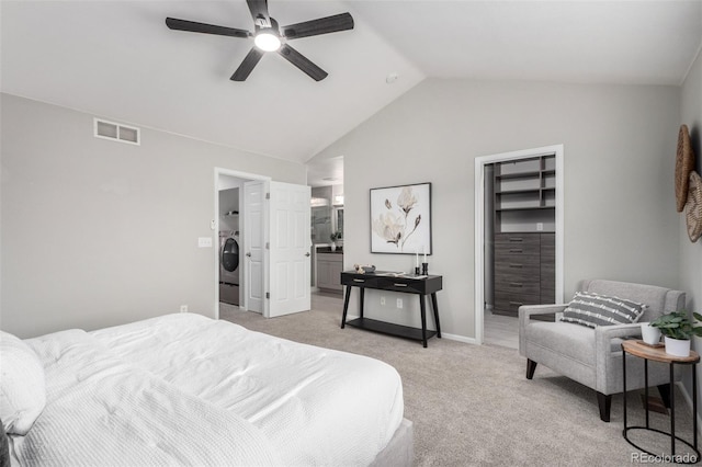 bedroom with lofted ceiling, ceiling fan, connected bathroom, washer / dryer, and light colored carpet