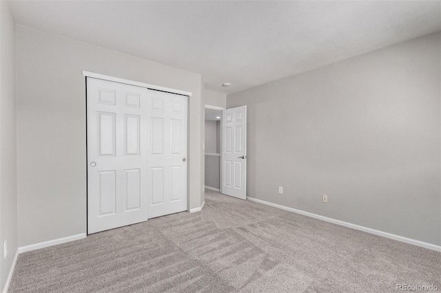 unfurnished bedroom featuring light colored carpet and a closet