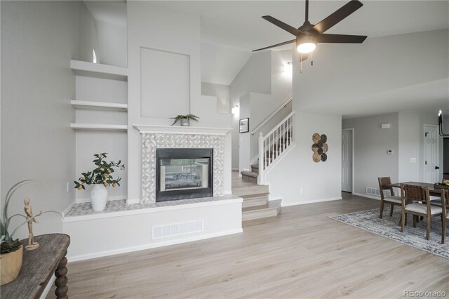 329 Lodgewood Ln, Lafayette, CO 80026 - living area with stairway, wood finished floors, a tiled fireplace, a ceiling fan, and baseboards