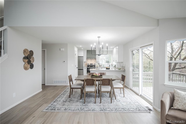329 Lodgewood Ln, Lafayette, CO 80026 - dining space featuring light wood-style flooring, a chandelier, baseboards, and vaulted ceiling
