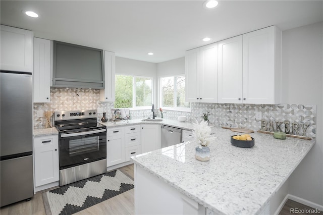 329 Lodgewood Ln, Lafayette, CO 80026 - kitchen with appliances with stainless steel finishes, a peninsula, white cabinetry, light wood-style floors, and recessed lighting