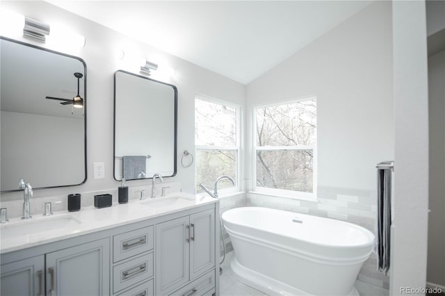 329 Lodgewood Ln, Lafayette, CO 80026 - bathroom featuring ceiling fan, a freestanding tub, vaulted ceiling, double vanity, and tile walls