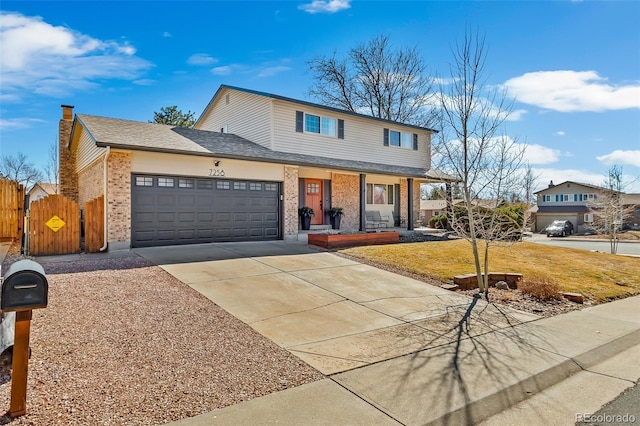 traditional home with a garage, concrete driveway, fence, a front lawn, and brick siding