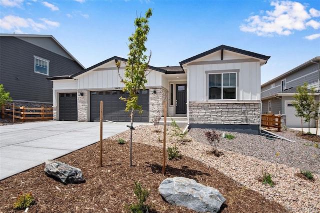 3443 N Gold Bug Ct, Aurora, CO 80019 - view of front facade with stone siding, fence, a garage, board and batten siding, and driveway