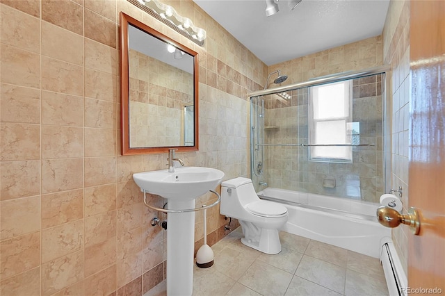 bathroom with tile walls, toilet, a baseboard heating unit, enclosed tub / shower combo, and tile patterned flooring