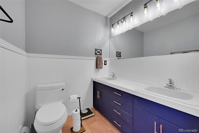 full bathroom featuring a wainscoted wall, tile patterned flooring, a sink, and toilet