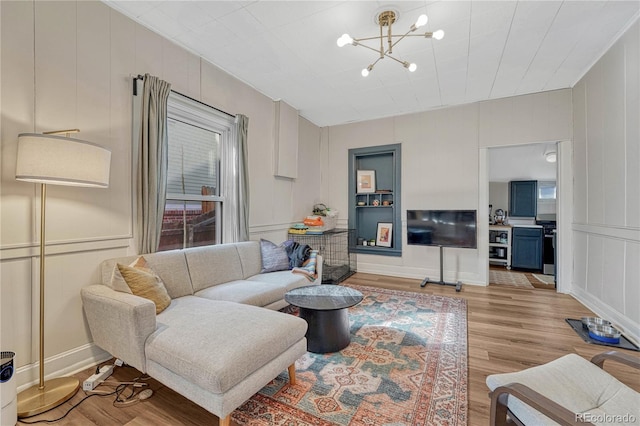 living room with a decorative wall, light wood finished floors, and an inviting chandelier