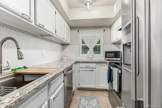 11105 E Alameda Ave Unit 204, Aurora, CO 80012 - kitchen with appliances with stainless steel finishes, a sink, light tile patterned flooring, white cabinetry, and backsplash