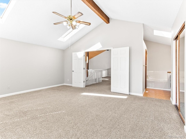 unfurnished bedroom featuring carpet floors, a skylight, beam ceiling, and baseboards