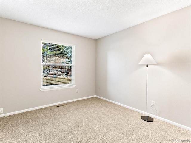 spare room featuring a textured ceiling, carpet flooring, visible vents, and baseboards