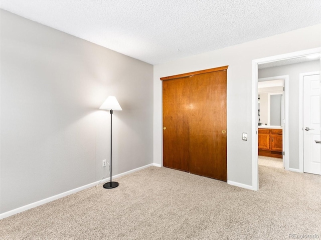 unfurnished bedroom with carpet floors, a closet, baseboards, and a textured ceiling