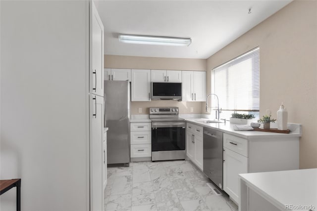 kitchen featuring stainless steel appliances, a sink, white cabinets, marble finish floor, and light countertops