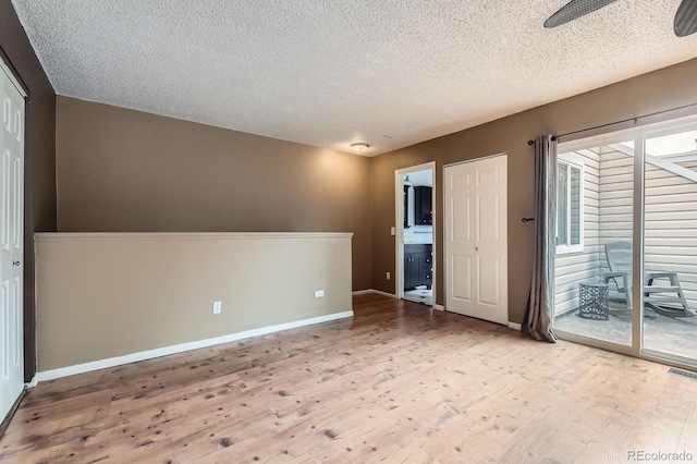 spare room with baseboards, visible vents, a textured ceiling, and wood finished floors