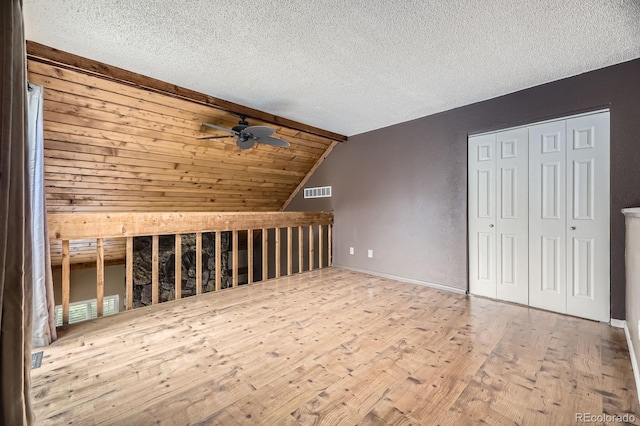 bonus room featuring wood finished floors, a textured ceiling, visible vents, ceiling fan, and lofted ceiling