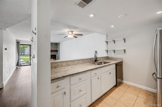 401 S Kalispell Way Unit 206, Aurora, CO 80017 - kitchen with freestanding refrigerator, a ceiling fan, open shelves, white cabinets, and a stone fireplace