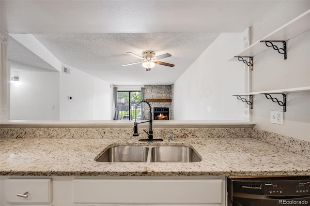 401 S Kalispell Way Unit 206, Aurora, CO 80017 - kitchen with dishwashing machine, ceiling fan, a textured ceiling, a stone fireplace, and white cabinetry