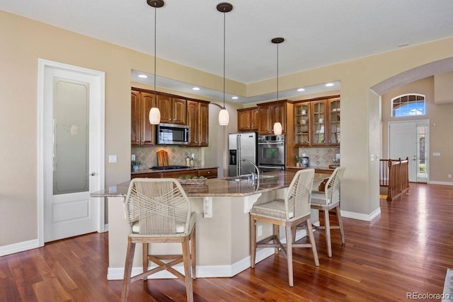 7472 Iridium Way, Castle Rock, CO 80108 - kitchen with appliances with stainless steel finishes, a breakfast bar area, dark wood-type flooring, and tasteful backsplash