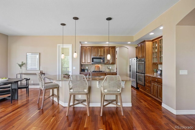 7472 Iridium Way, Castle Rock, CO 80108 - kitchen with stainless steel appliances, a breakfast bar, dark wood-style flooring, and glass insert cabinets