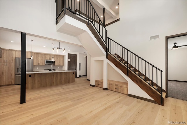 stairway with a high ceiling, hardwood / wood-style flooring, and ceiling fan