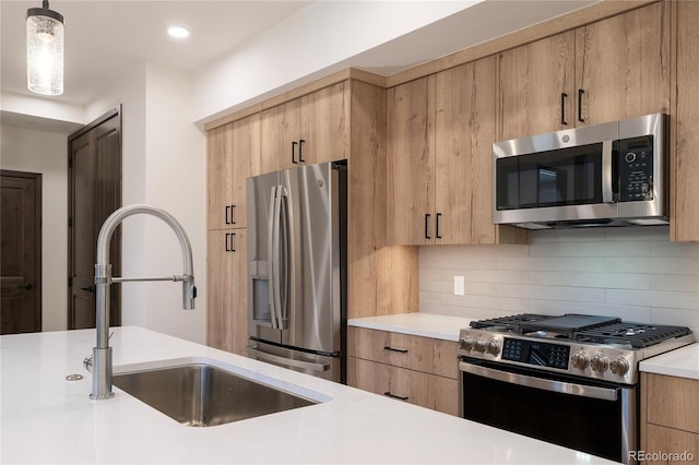 kitchen with pendant lighting, stainless steel appliances, sink, and backsplash