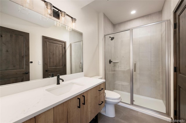 bathroom with vanity, a shower with door, and toilet