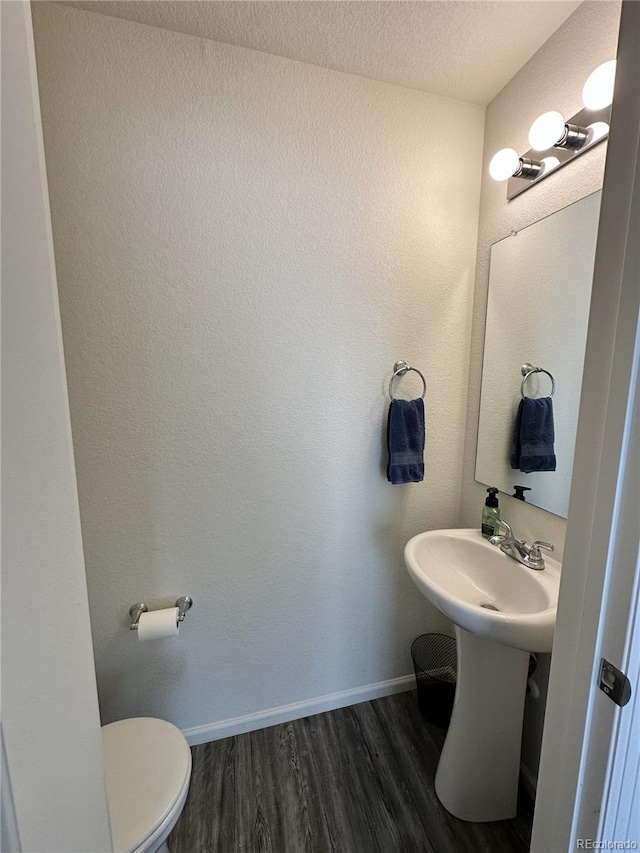 5121 N Yampa St, Denver, CO 80249 - half bathroom with wood finished floors, toilet, baseboards, a textured ceiling, and a sink