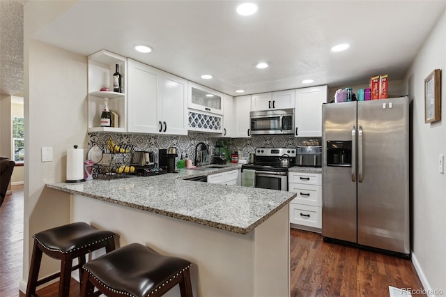 8452 Everett Way Unit C, Arvada, CO 80005 - kitchen with stainless steel appliances, a peninsula, open shelves, white cabinetry, and light stone countertops