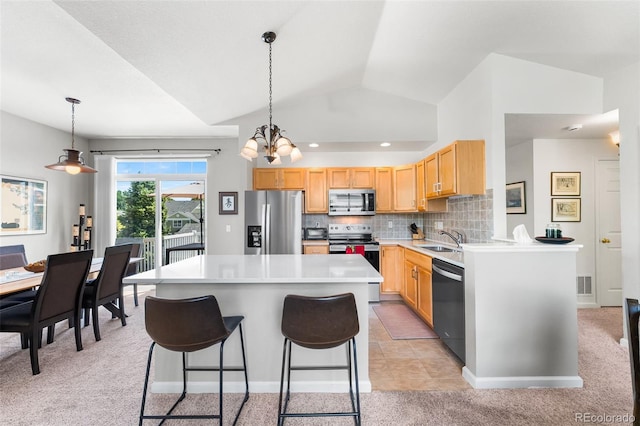 4501 Nelson Rd Unit 2201, Longmont, CO 80503 - kitchen with stainless steel appliances, vaulted ceiling, light brown cabinetry, a center island, and tasteful backsplash