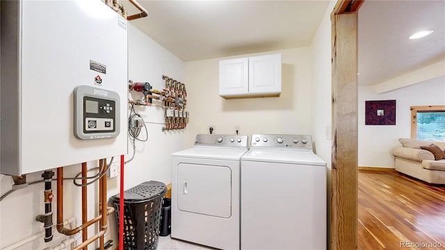 7 Rock Canyon Rd, Drake, CO 80515 - laundry area with tankless water heater, washer and clothes dryer, cabinet space, and light wood finished floors