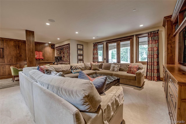 living area with recessed lighting, light carpet, and wood walls