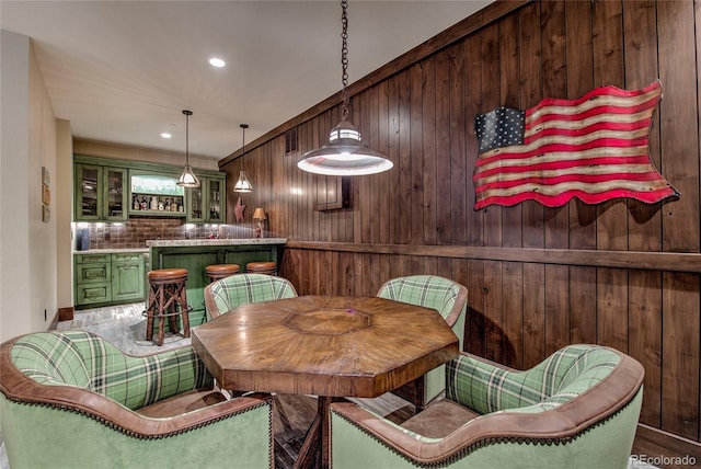 dining area featuring wet bar, wooden walls, and recessed lighting