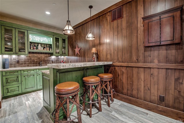 bar with decorative backsplash, light wood-style flooring, visible vents, and wood walls