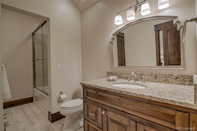 bathroom with toilet, wood finished floors, combined bath / shower with glass door, baseboards, and vanity