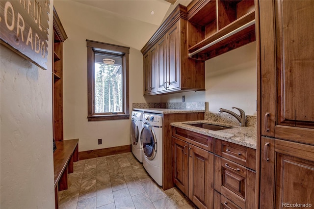 laundry area featuring cabinet space, washing machine and dryer, baseboards, and a sink