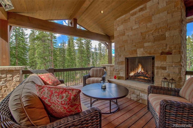 sunroom with lofted ceiling with beams, wooden ceiling, and an outdoor stone fireplace