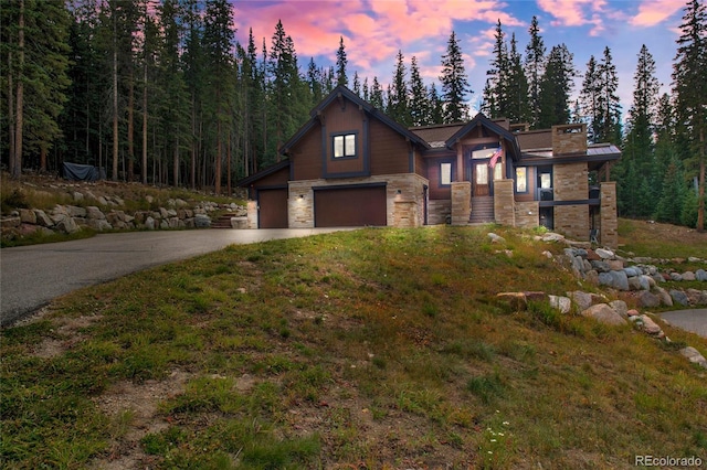 view of front of home featuring stone siding, an attached garage, and driveway