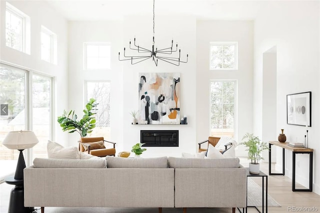 3530 Fenton St, Wheat Ridge, CO 80212 - living room featuring a high ceiling, a chandelier, light wood finished floors, and a glass covered fireplace