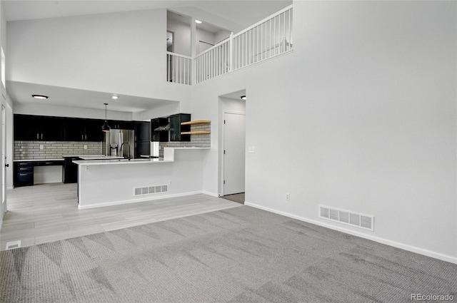 kitchen featuring dark cabinets, stainless steel refrigerator with ice dispenser, baseboards, and open floor plan
