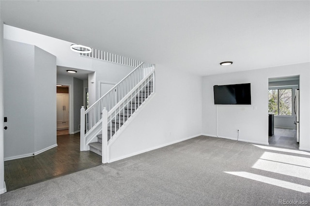 unfurnished living room with carpet flooring, stairway, and baseboards