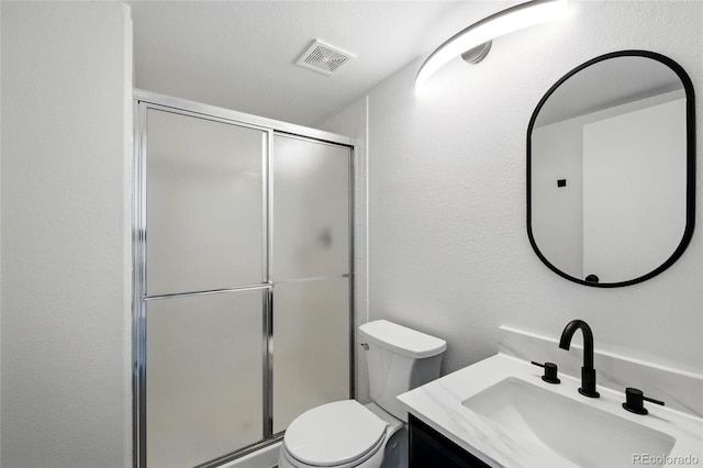 full bath with a shower stall, a textured wall, vanity, and toilet
